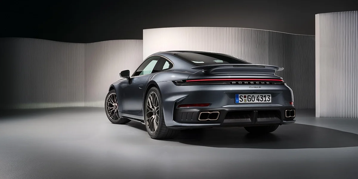 Rear three-quarter view of Porsche 911 Turbo S coupe with LED taillights, quad exhaust system, and active rear spoiler.